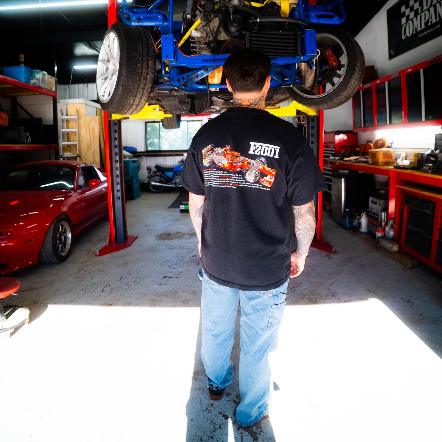 Person working on a car in a garage with tools and equipment around