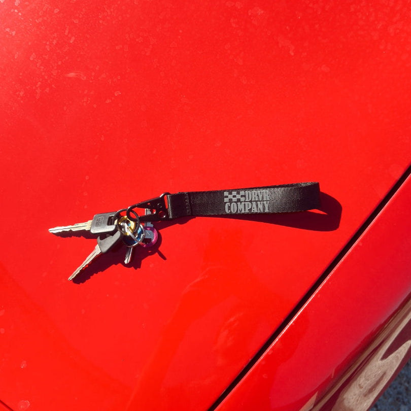 Black and grey lanyard with car keys laying on hood of car
