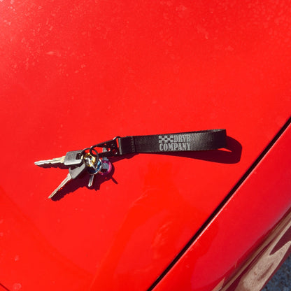 Black and grey lanyard with car keys laying on hood of car