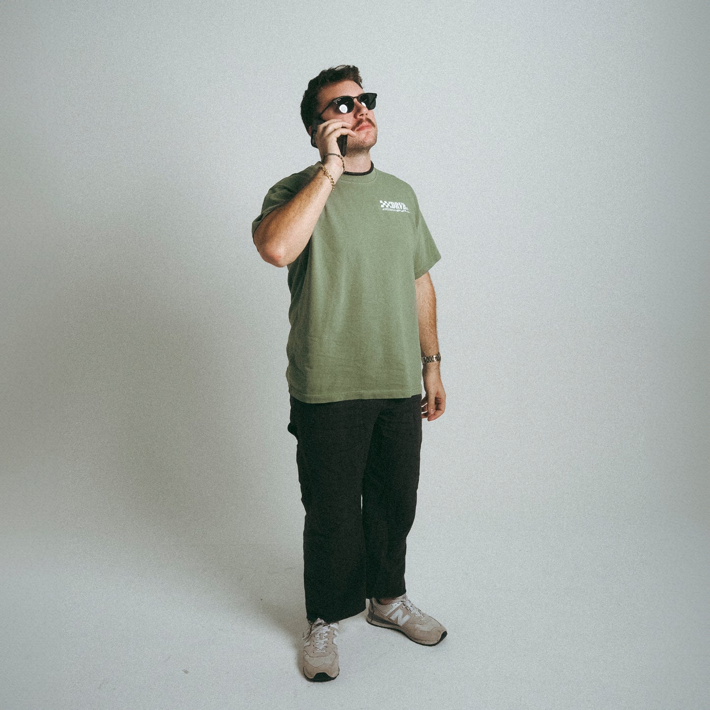 Man holding phone in sunglasses wearing DRVR CO green heavyweight shirt