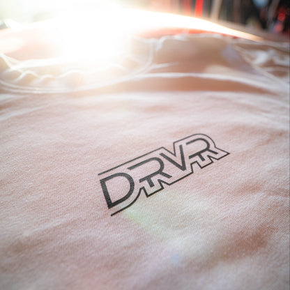 Close-up of a white shirt with 'DRVR' logo on a blurred background