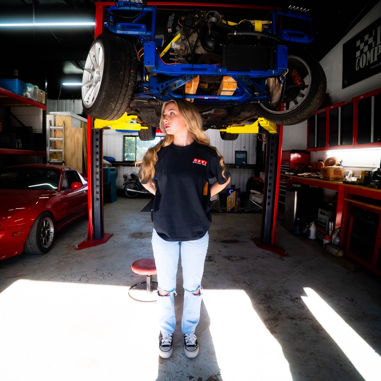 Person standing in a garage with a car on a lift
