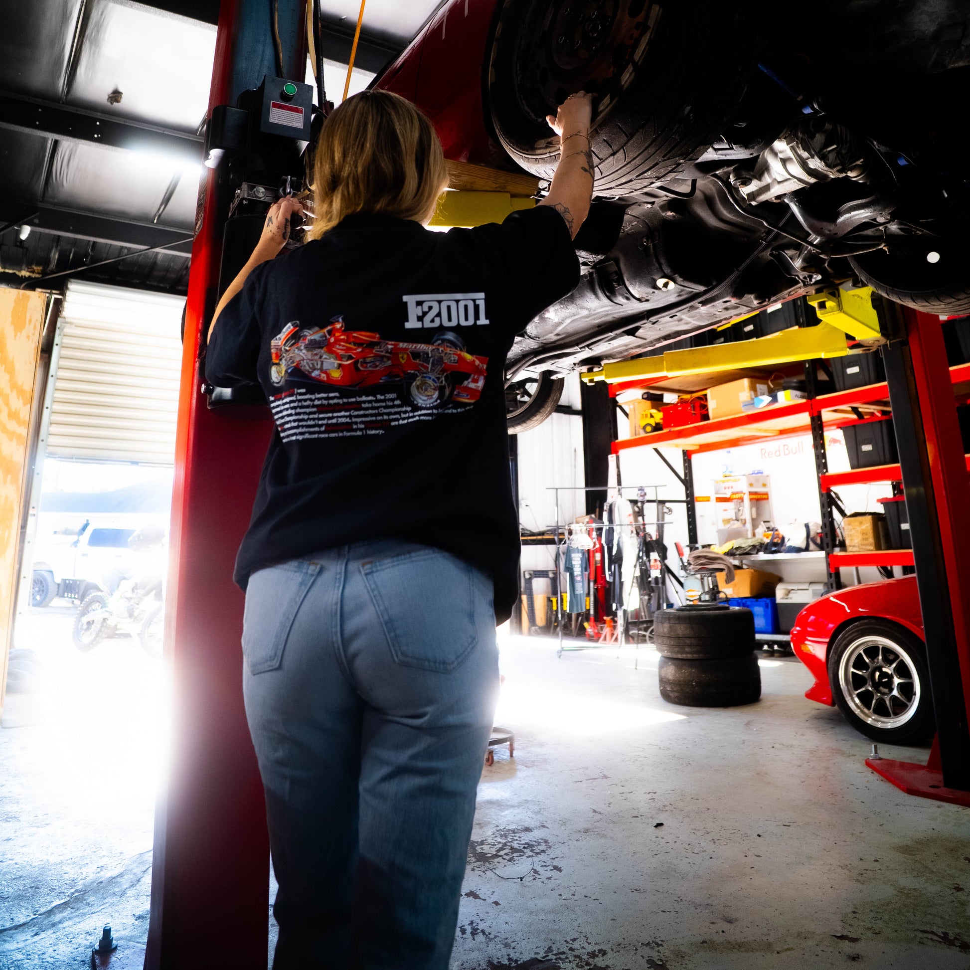 Person working on a car under a lift in a garage