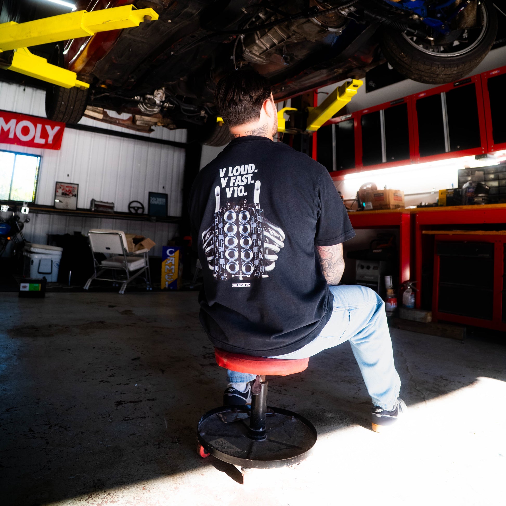 Person working on a car under a举起的车架 in a garage.