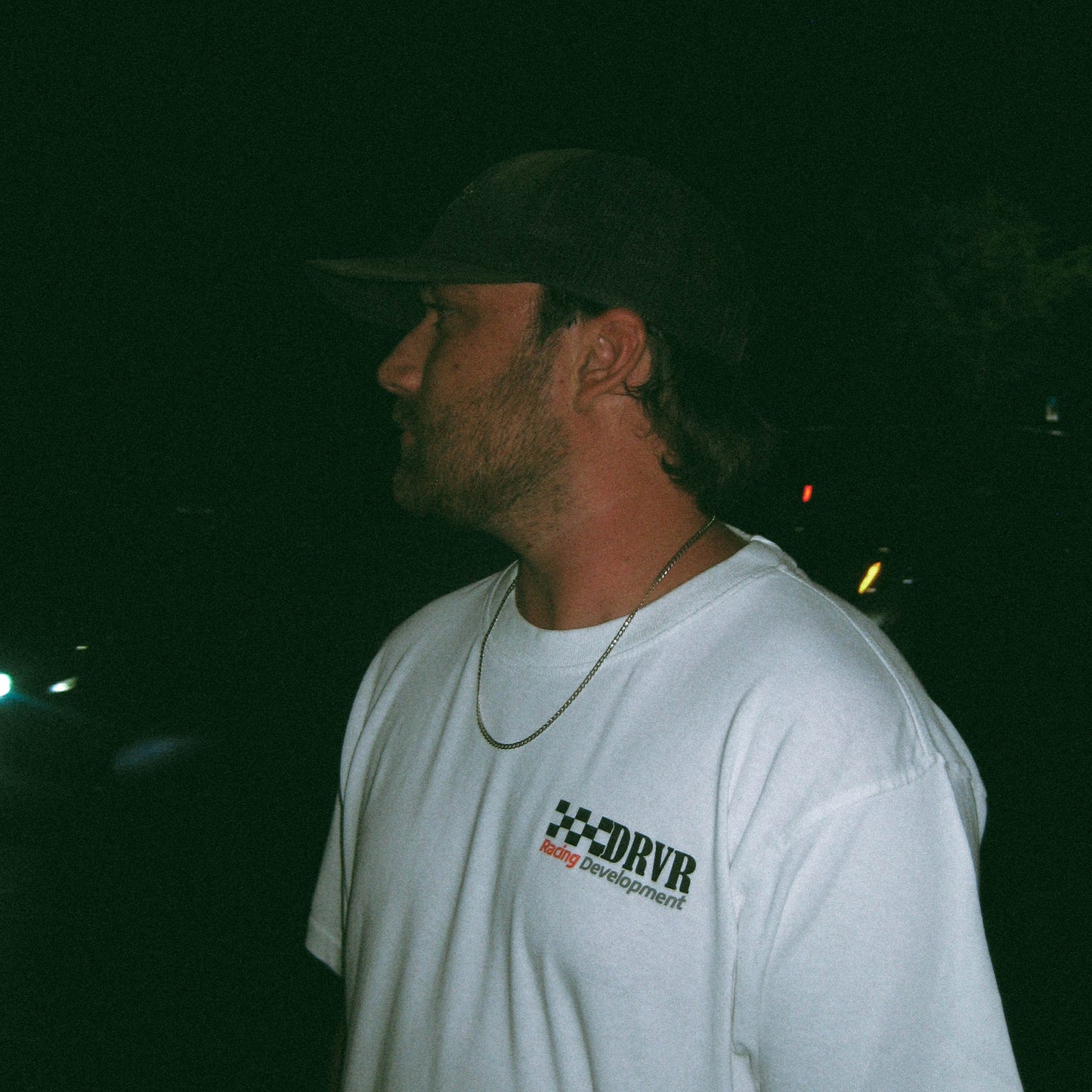 Man wearing a white t-shirt with a logo at night