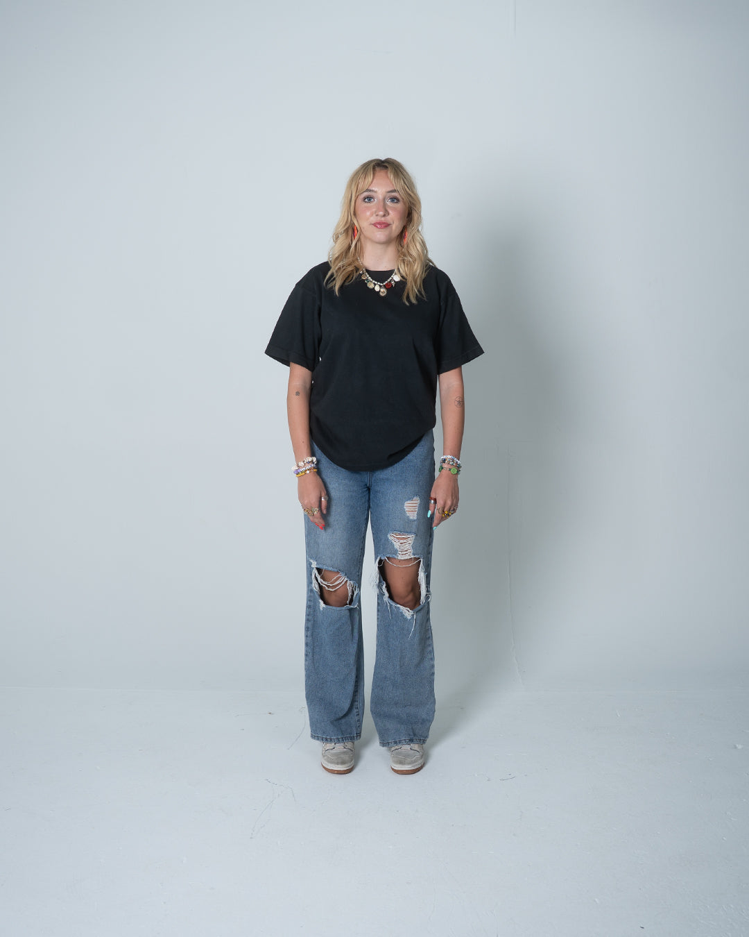 Person wearing a black t-shirt and ripped jeans on a white background