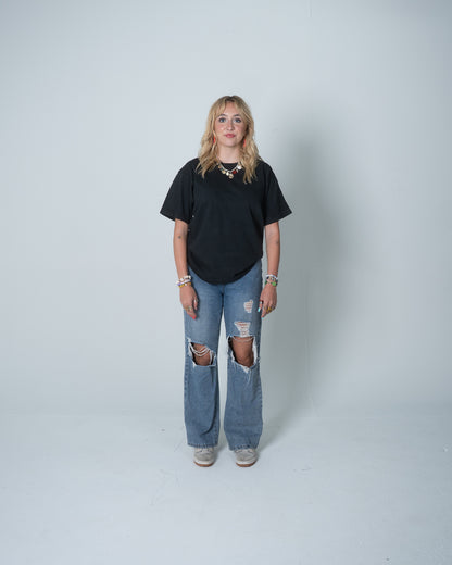 Person wearing a black t-shirt and ripped jeans on a white background