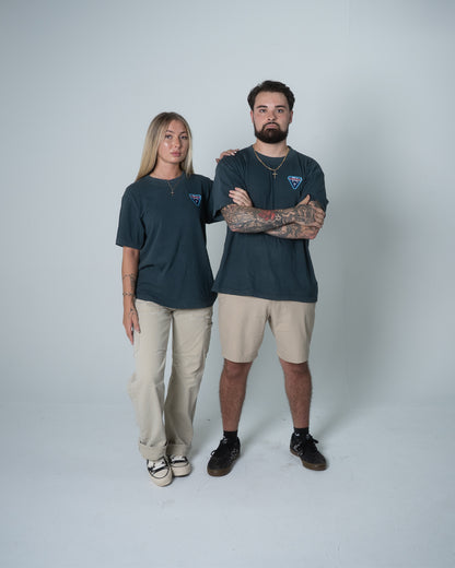 Two people wearing matching dark shirts and light pants on a plain background