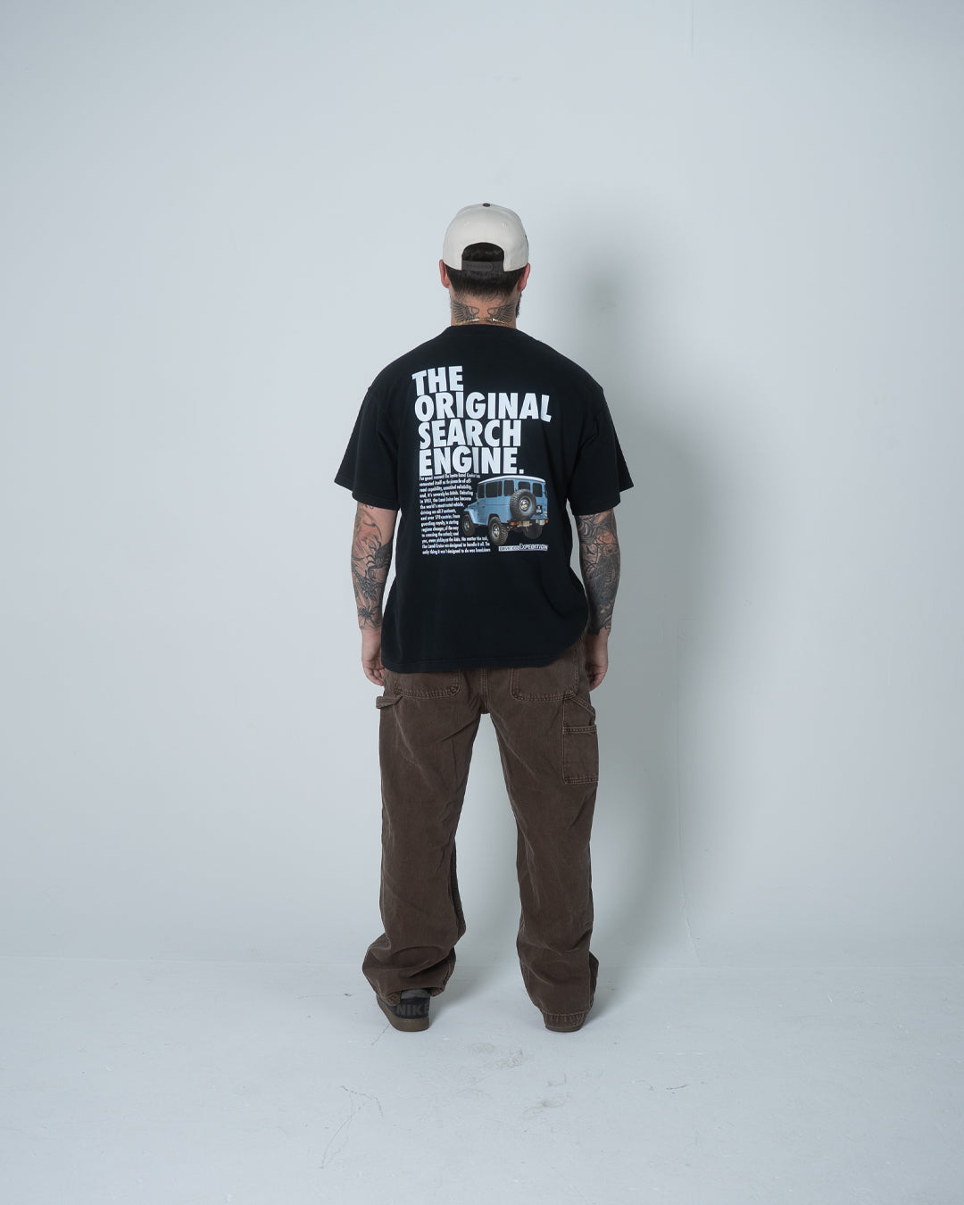 Person wearing a black t-shirt with text and graphics, standing against a white background