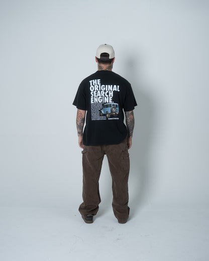 Person wearing a black t-shirt with text and graphics, standing against a white background