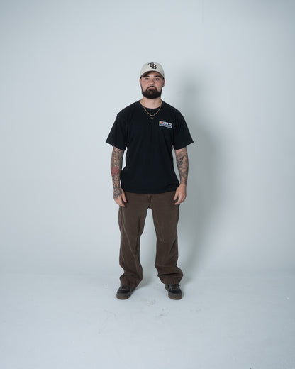 Man wearing a black t-shirt, brown pants, and a cap on a white background