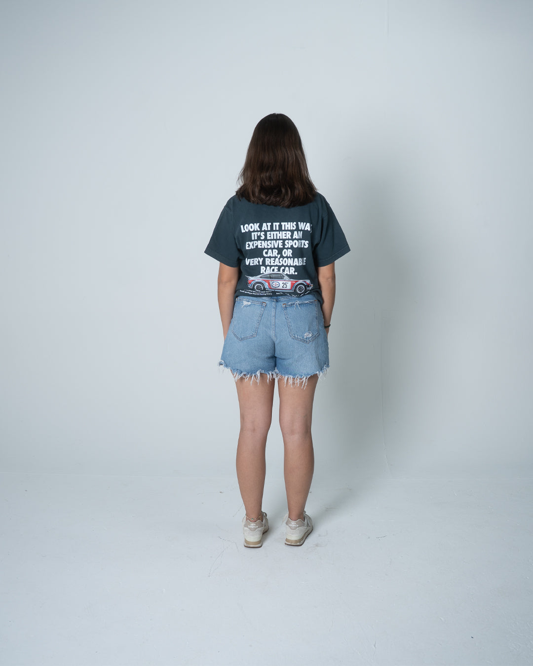 Person wearing a graphic t-shirt and denim shorts on a white background