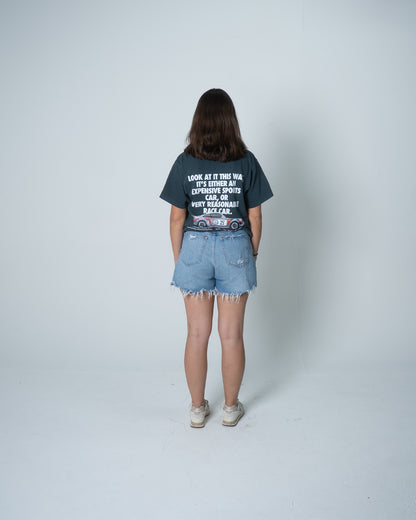 Person wearing a graphic t-shirt and denim shorts on a white background