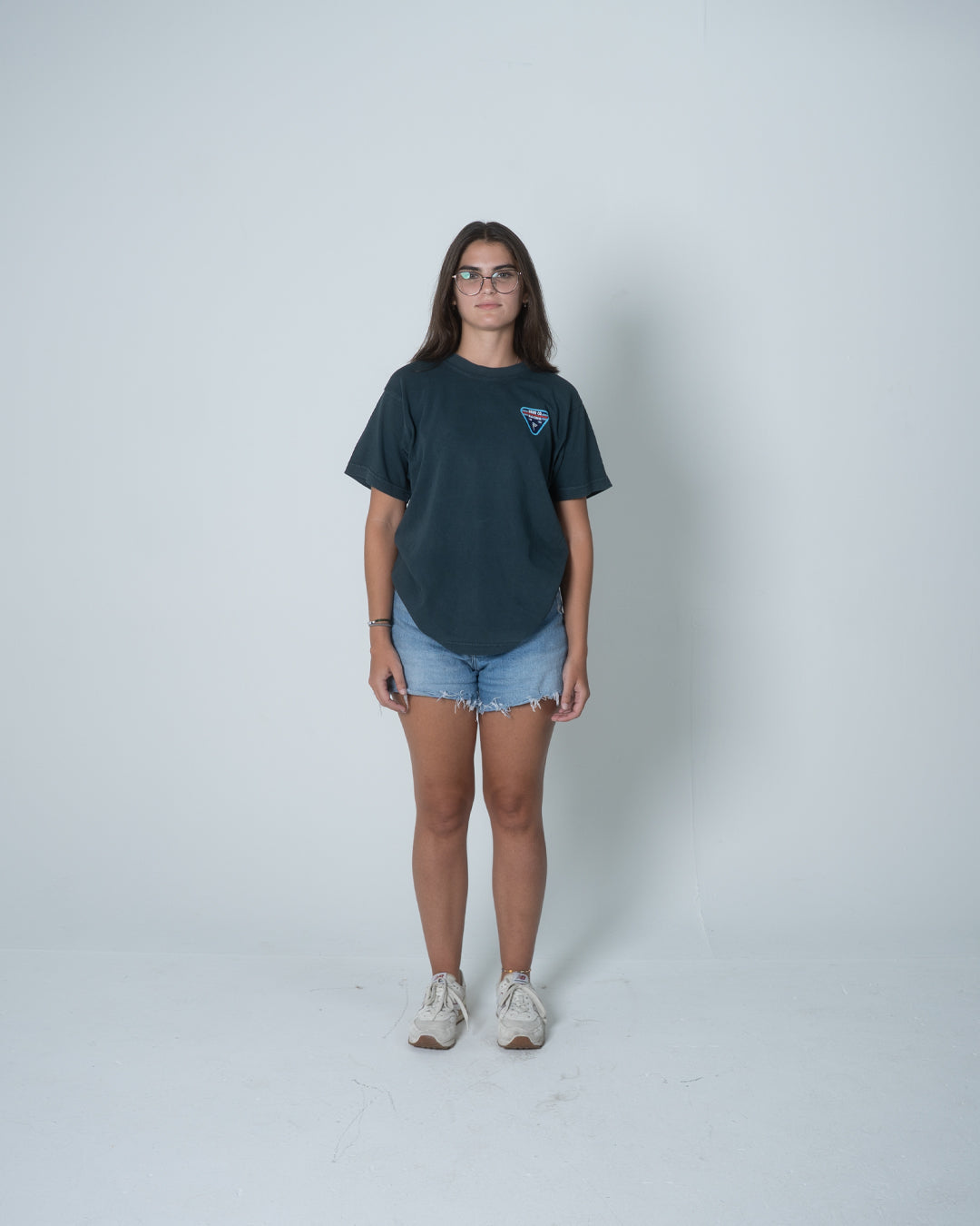 Person wearing a dark t-shirt and denim shorts on a white background