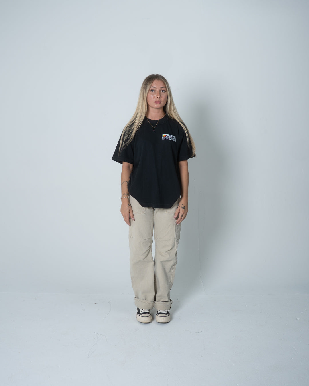 Person wearing a black t-shirt and beige pants on a white background