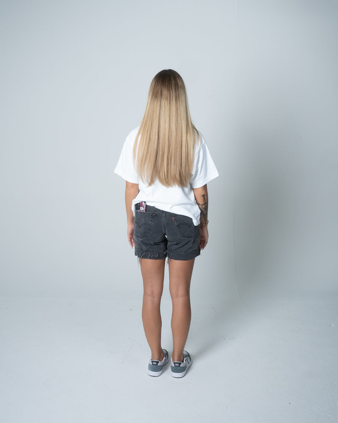 Person wearing a white t-shirt and denim shorts on a plain background