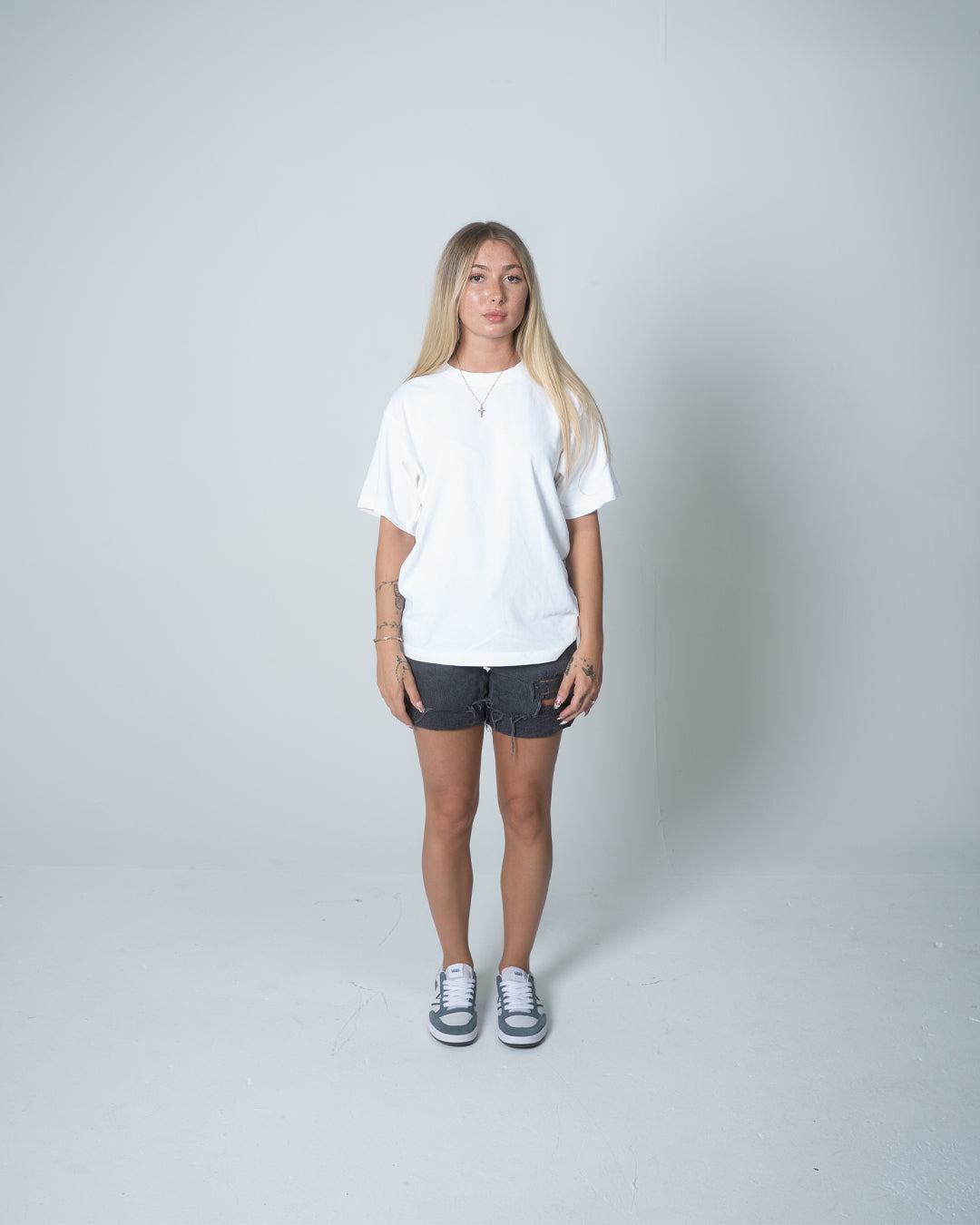 Person wearing a white t-shirt and dark shorts on a plain background