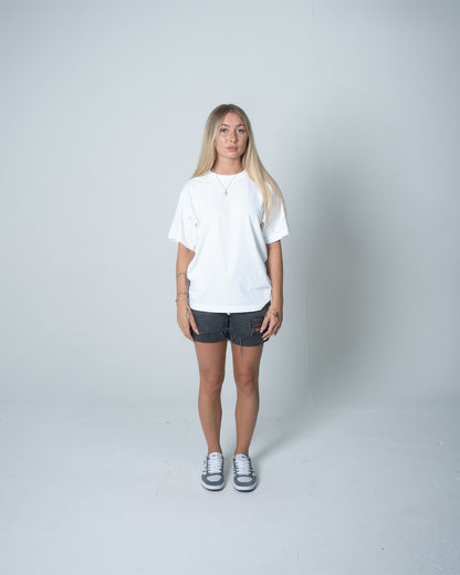 Person wearing a white t-shirt and dark shorts on a plain background